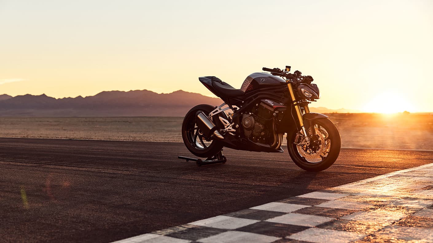 Triumph Speed Triple 1200 RS on the track with the sunset in the distance